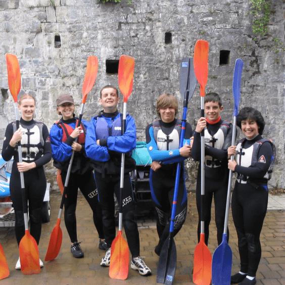 Youngsters in wetsuits with paddles